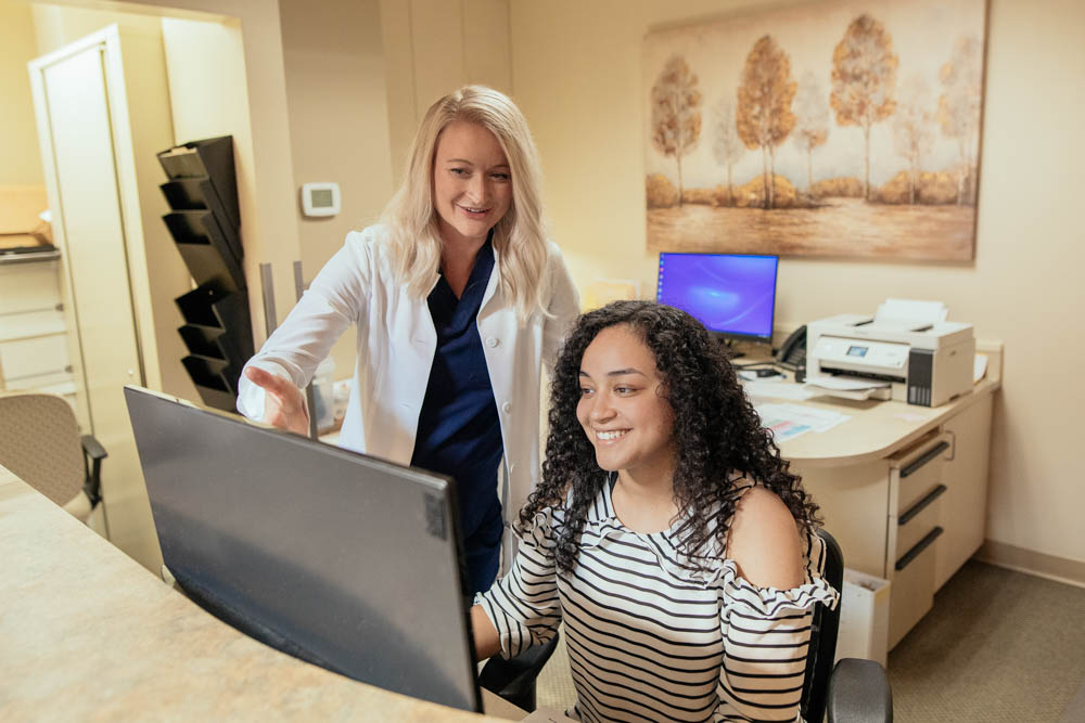 Dr. Whitney Forsythe discusses something on a monitor with a staff member