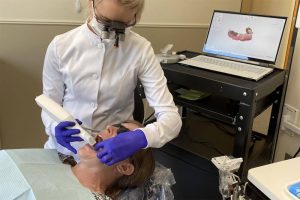 A dental assistant uses a Trios 3Shape Scanner to take digital impressions of a dental patient's teeth