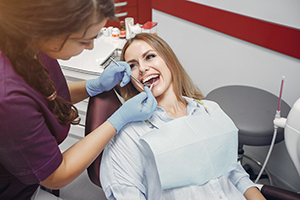 female dental patient sits in the dental chair for a teeth cleaning and dental checkup